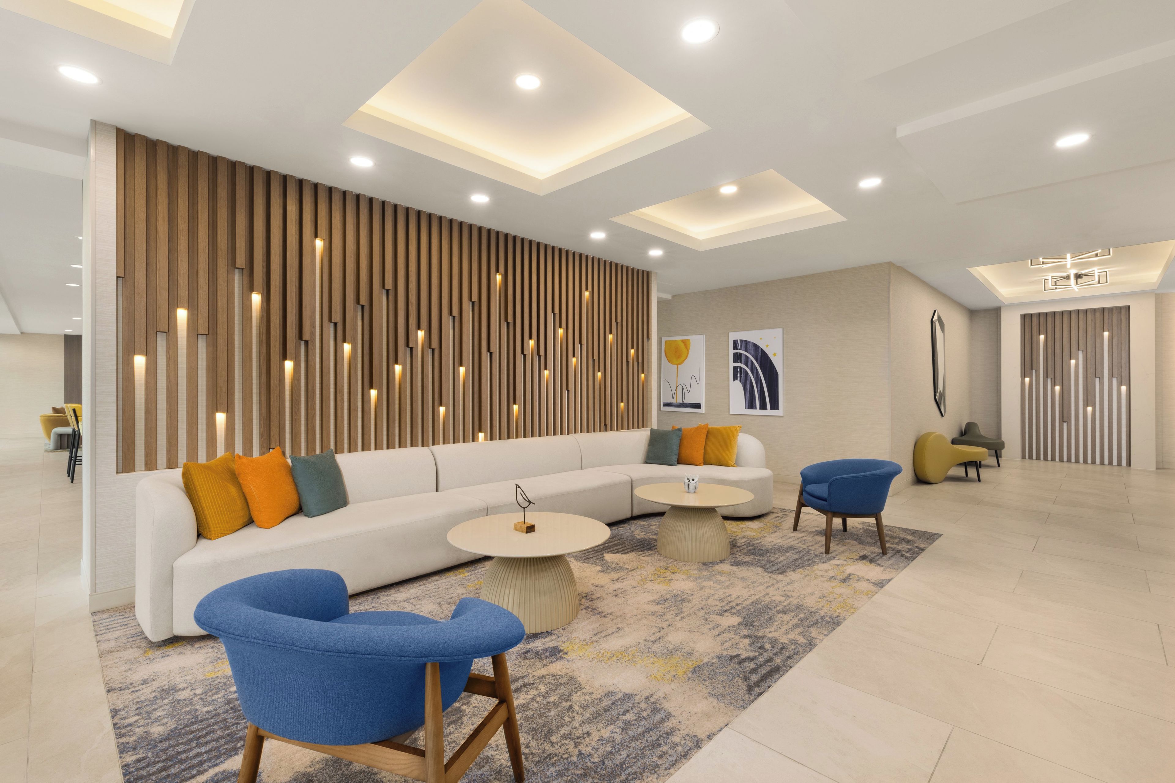 Un área de estar moderna con un sofá blanco, sillones azules y una mesa de centro redonda.