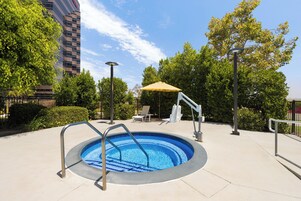 A swimming pool with a metal ladder, surrounded by a paved area with lounge chairs and a canopy.