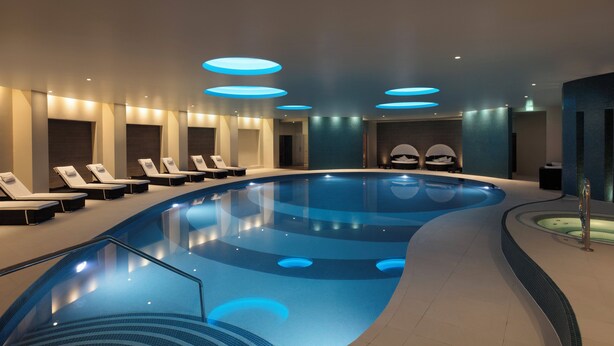 A modern indoor swimming pool with lounge chairs and recessed lighting. - Leonardo Hotel and Conference Venue Hinckley Island (Hinckley)