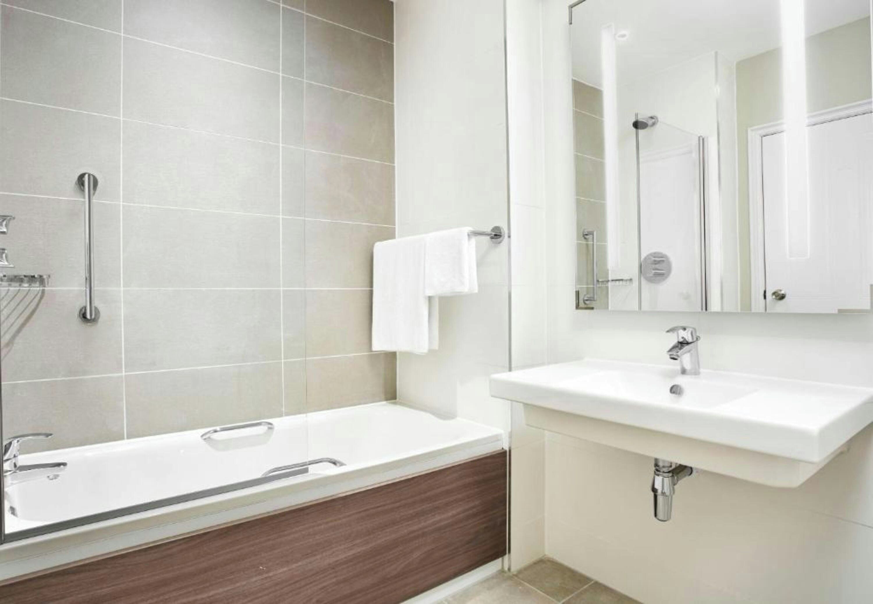 A modern bathroom with a bathtub, a sink, and a mirror.