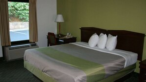 Een hotelkamer met een bed, bureau, lamp en raam met gordijnen.