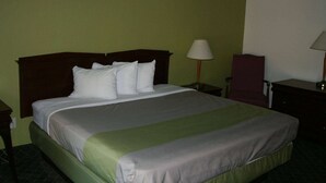 Een hotelkamer met een bed, nachtkastje, stoel en lamp.