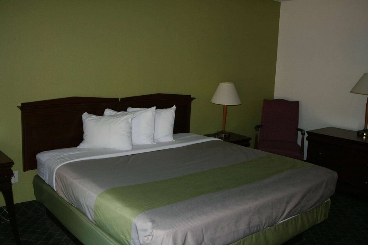 Een hotelkamer met een bed, nachtkastje, stoel en lamp.