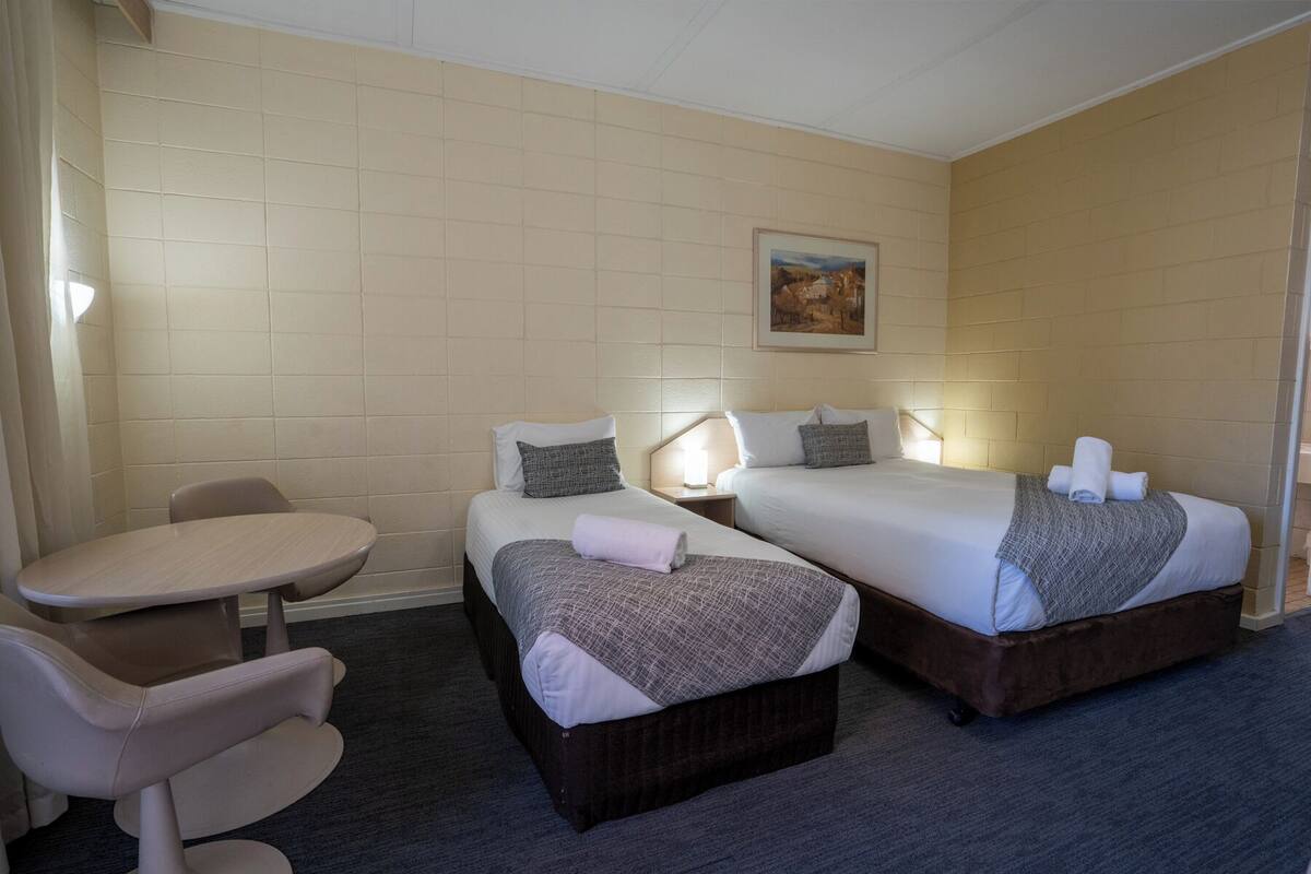 Ein Hotelzimmer mit zwei Betten, einem kleinen Tisch und einem Stuhl.