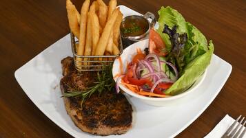 Un piatto con carne alla griglia, patatine fritte, un'insalata e salsa per intingere.