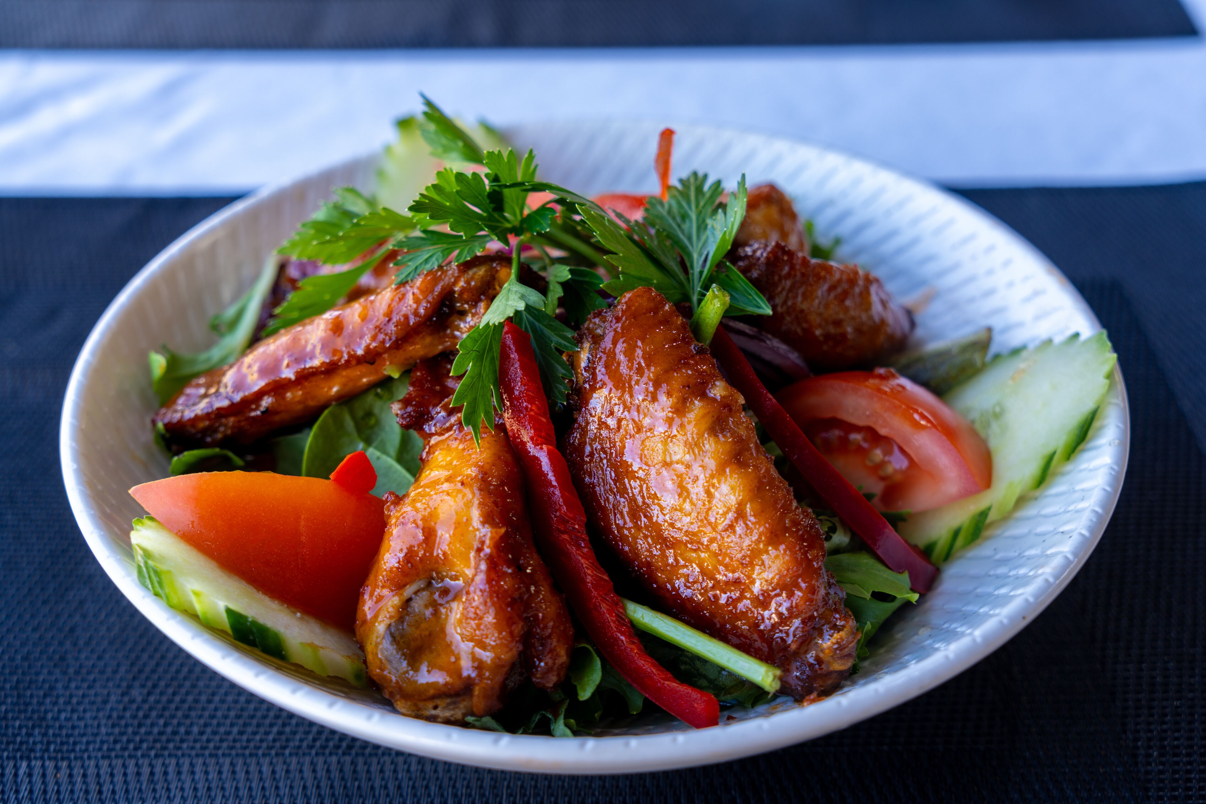 A plate of food with grilled chicken, vegetables, and herbs.