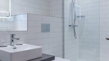 A modern bathroom with a white sink, toilet, and glass-enclosed shower.