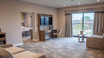 A spacious living area with a flat-screen TV, a desk, and a comfortable seating arrangement.