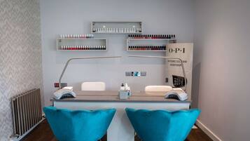 Ein Nagelstudio mit Empfangstresen, zwei Stühlen und Regalen voller Nagellack.