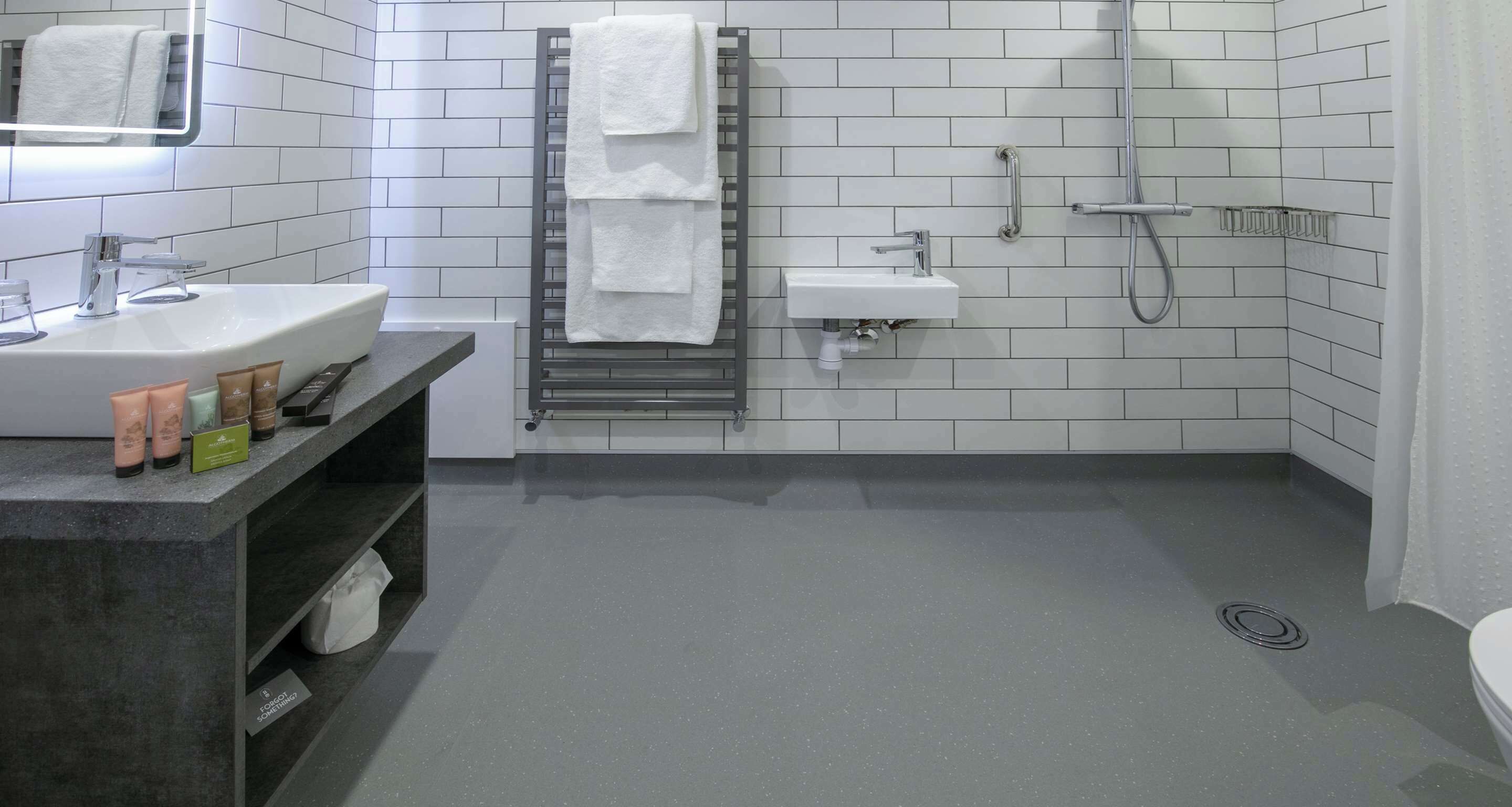 A modern bathroom with a large sink, a mirror, a towel rack, a shower, and a toilet.