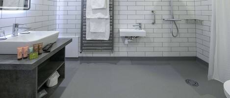 A modern bathroom with a large sink, a mirror, a towel rack, a shower, and a toilet.
