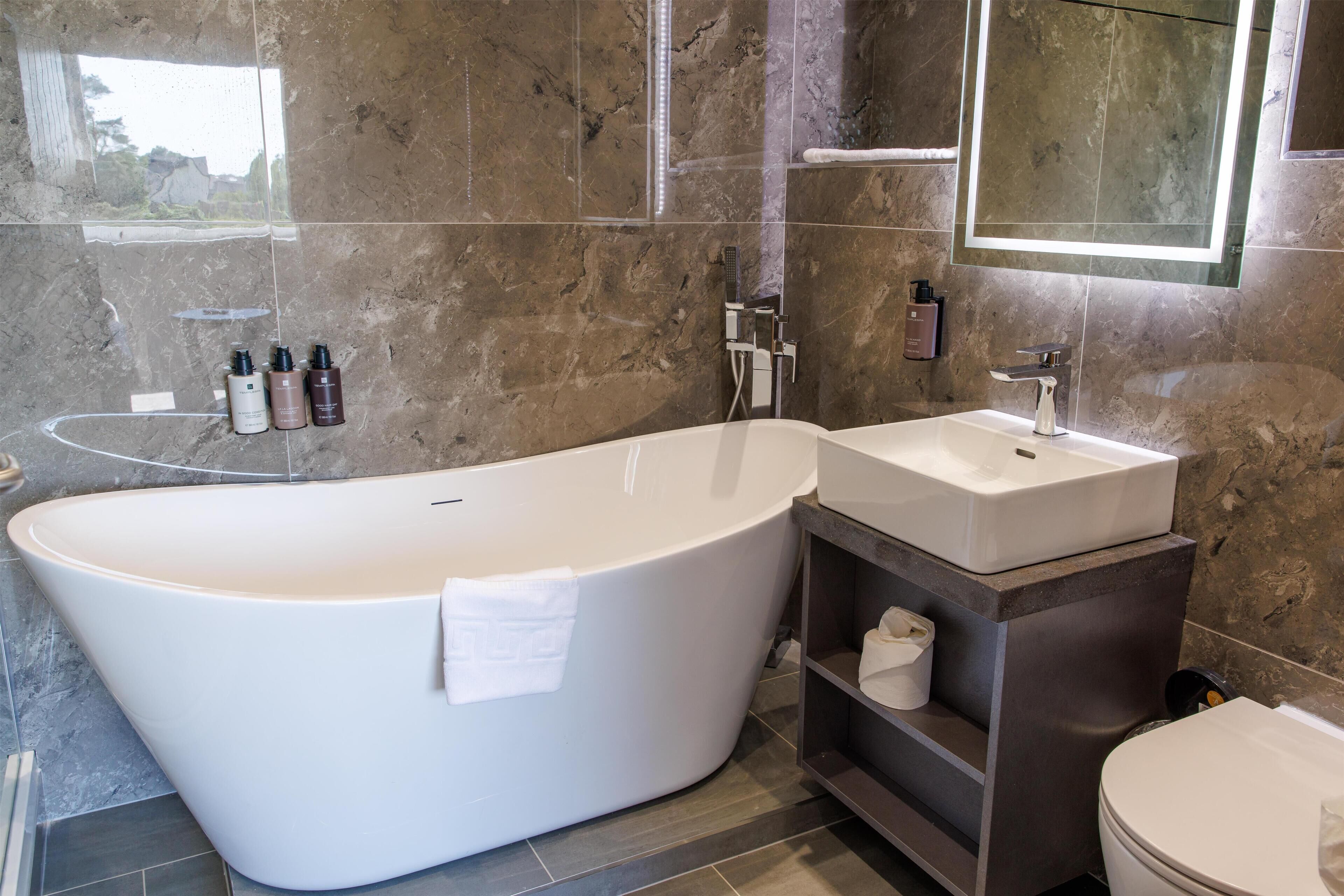 A modern bathroom with a freestanding bathtub, a sink, and a toilet.