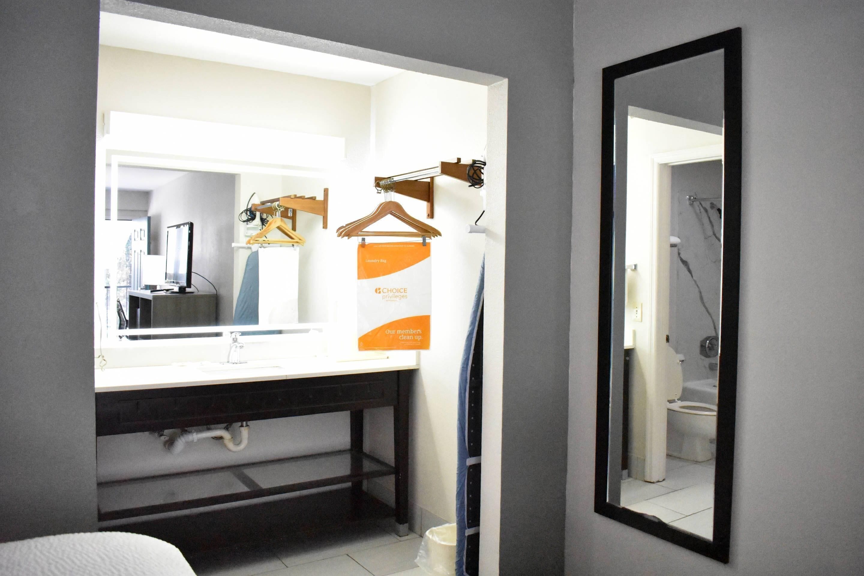 A bathroom with a mirror, a sink, and a towel rack.