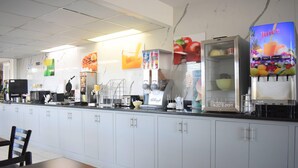 A breakfast bar with a juice dispenser, cereal boxes, and a coffee machine. - Quality Inn Manning I-95 (Manning)
