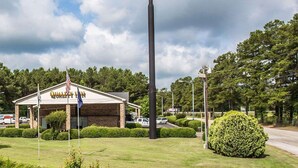 A Quality Inn sign, a building with a brick facade, and a well-maintained lawn. - Quality Inn Manning I-95 (Manning)