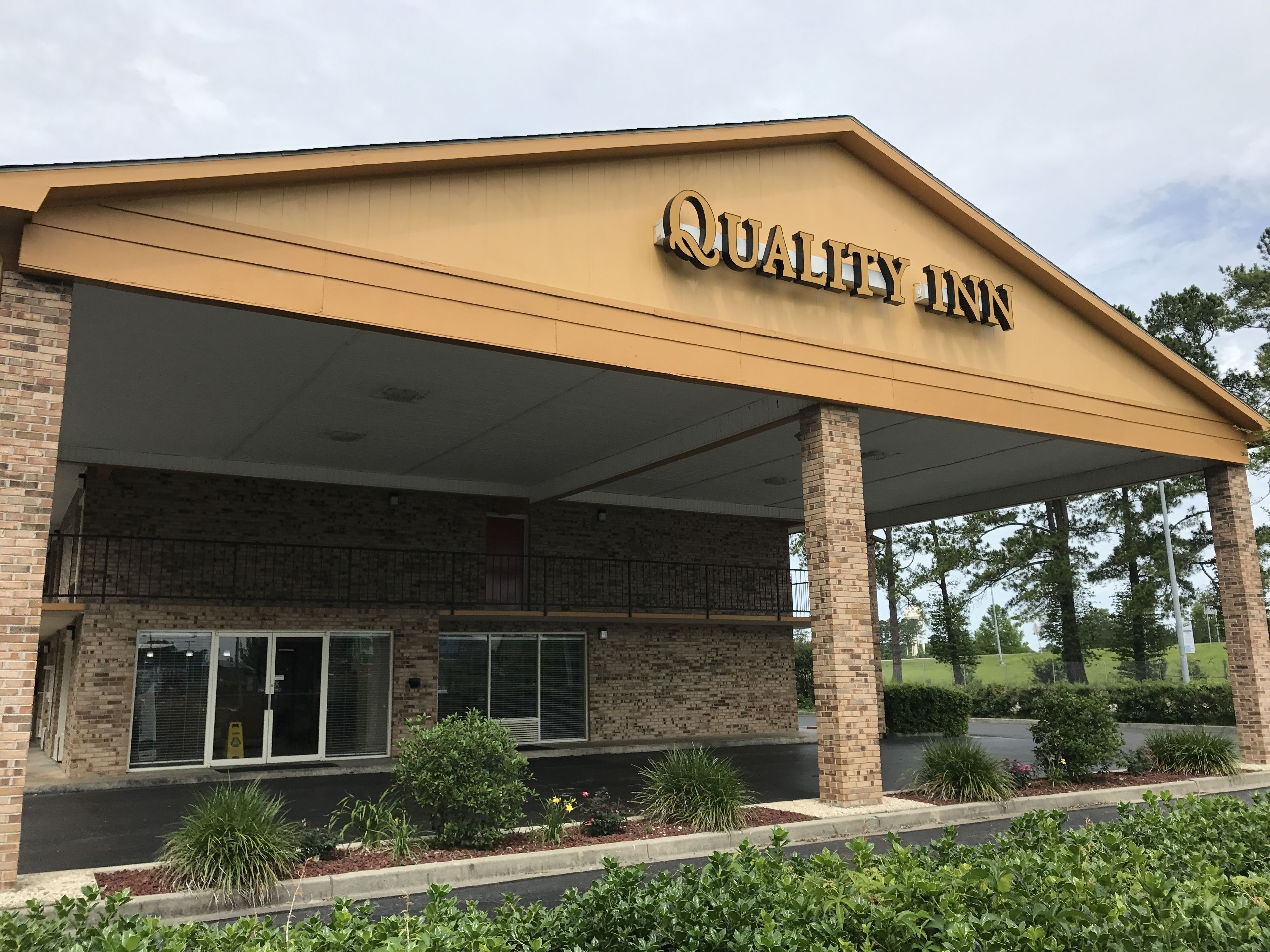 Un bâtiment en briques doté d’une entrée couverte et d’une enseigne indiquant « Quality Inn ».