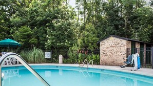 A swimming pool with a shallow water sign, a brick building, and a green umbrella. - Quality Inn Manning I-95 (Manning)