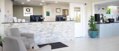Un área de recepción con mostrador de piedra, una computadora, un letrero que dice 'Calidad' y una mesa de recepción.