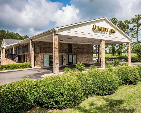 A hotel with a covered entrance, brick facade, and a sign that reads "Quality Inn."