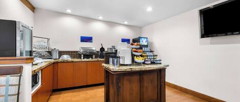 A modern kitchen with granite countertops, a built-in microwave, and a coffee station.