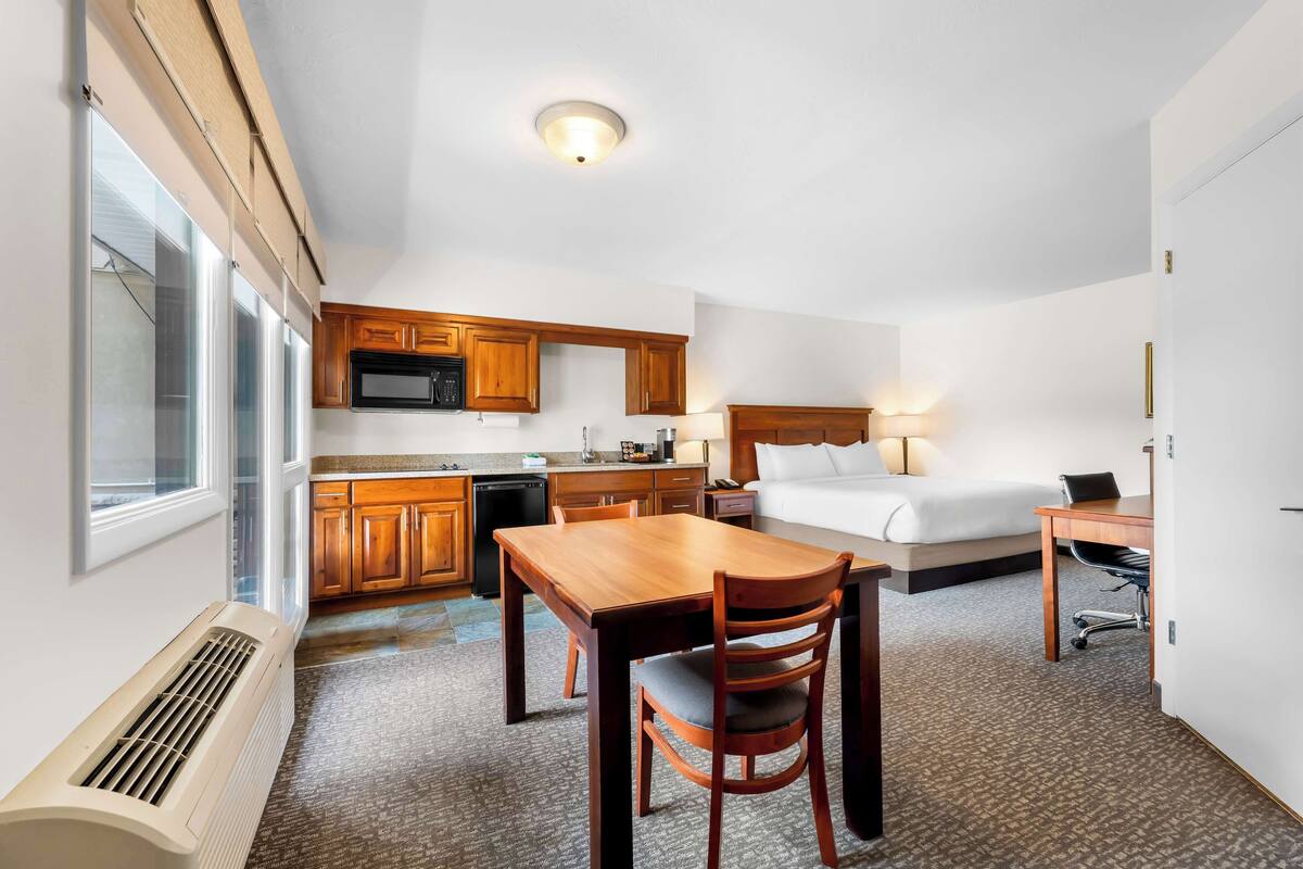 Une chambre d’hôtel équipée d’une kitchenette, d’un lit, d’un bureau et d’une chaise.