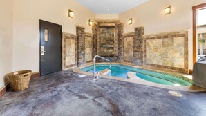Un área de spa con pared de piedra, piscina y puerta.