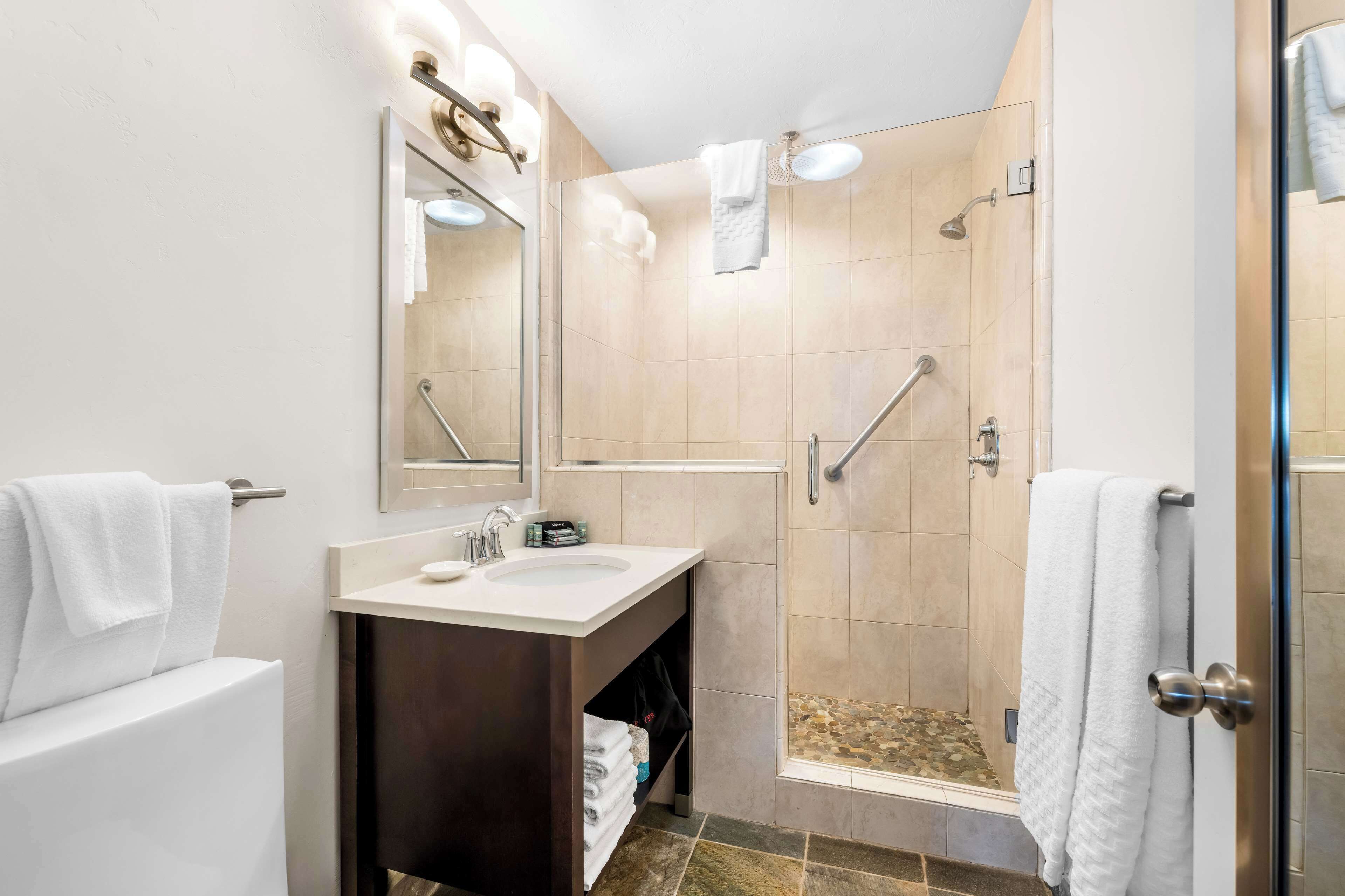 A modern bathroom with a sink, mirror, and shower.