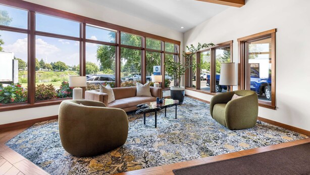 Un salón amplio con ventanas grandes, un sofá, dos sillones y una mesa de centro.