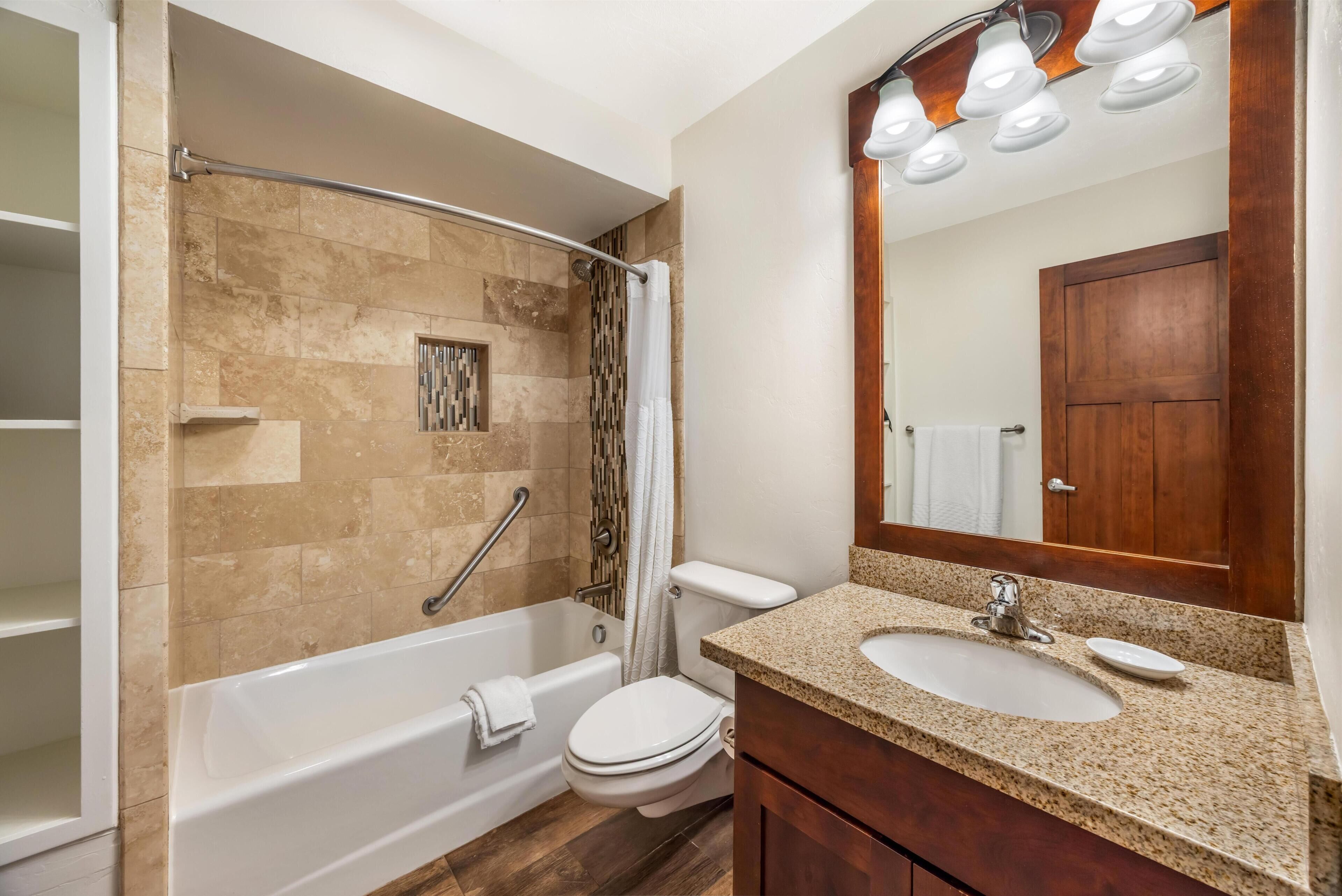 A bathroom with a bathtub, toilet, sink, and a mirror.