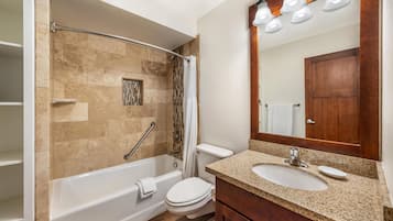 A bathroom with a bathtub, toilet, sink, and a mirror.