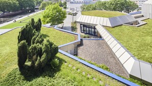 A modern building with a unique roof design, surrounded by green spaces and a river. - Parkhotel Pforzheim (Pforzheim)