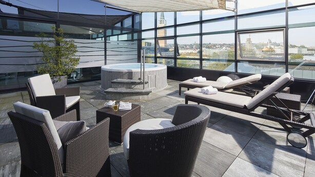 A rooftop terrace with wicker furniture, a hot tub, and a view of the cityscape. - Parkhotel Pforzheim (Pforzheim)