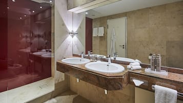 Un baño moderno con dos lavamanos, un espejo grande y una zona de ducha con mampara de vidrio.
