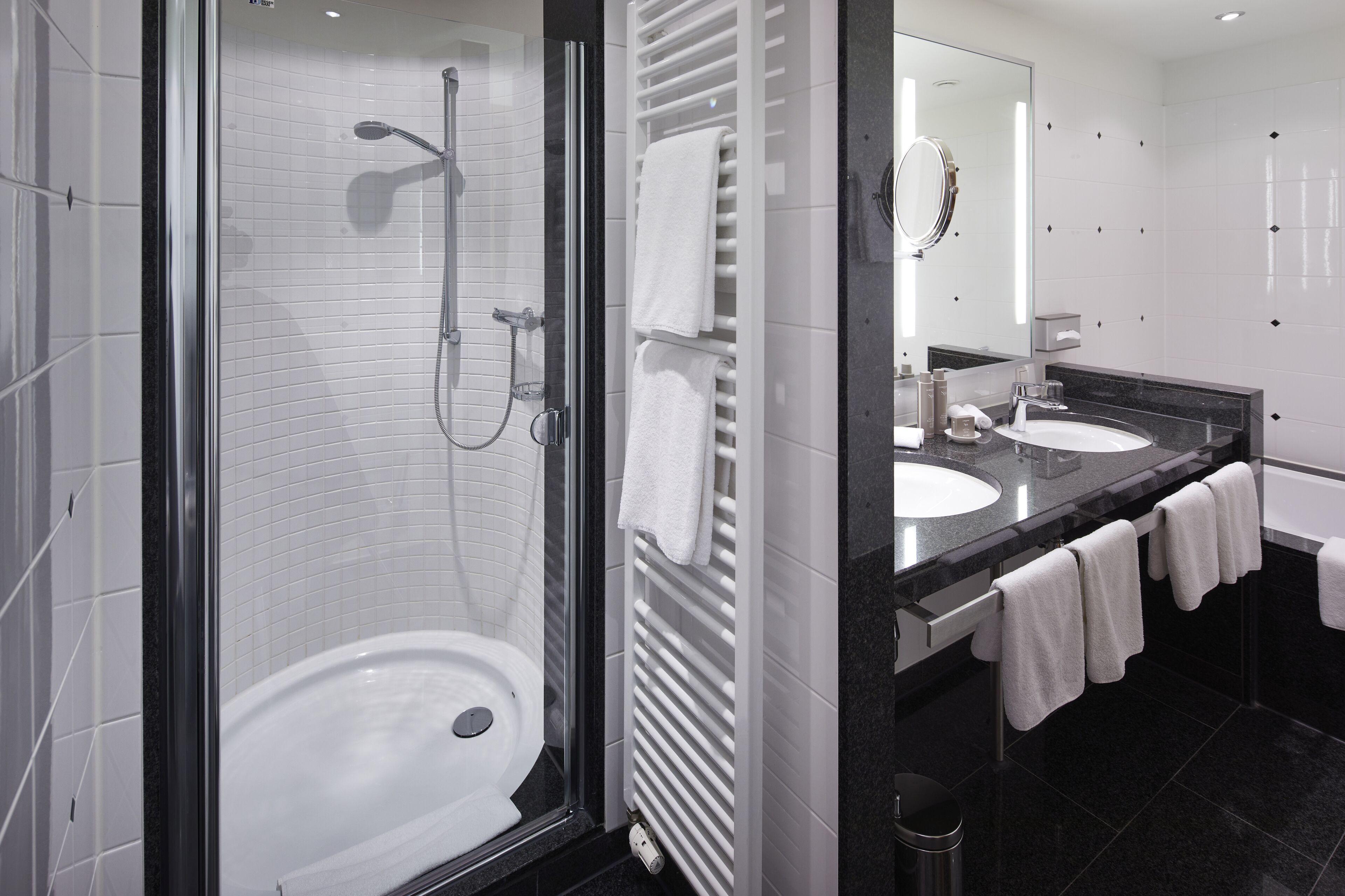 A modern bathroom with a glass-enclosed shower, a white sink, and a large mirror.