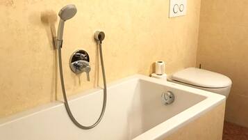 A standard hotel bathroom with a bathtub, a toilet, and a shower.