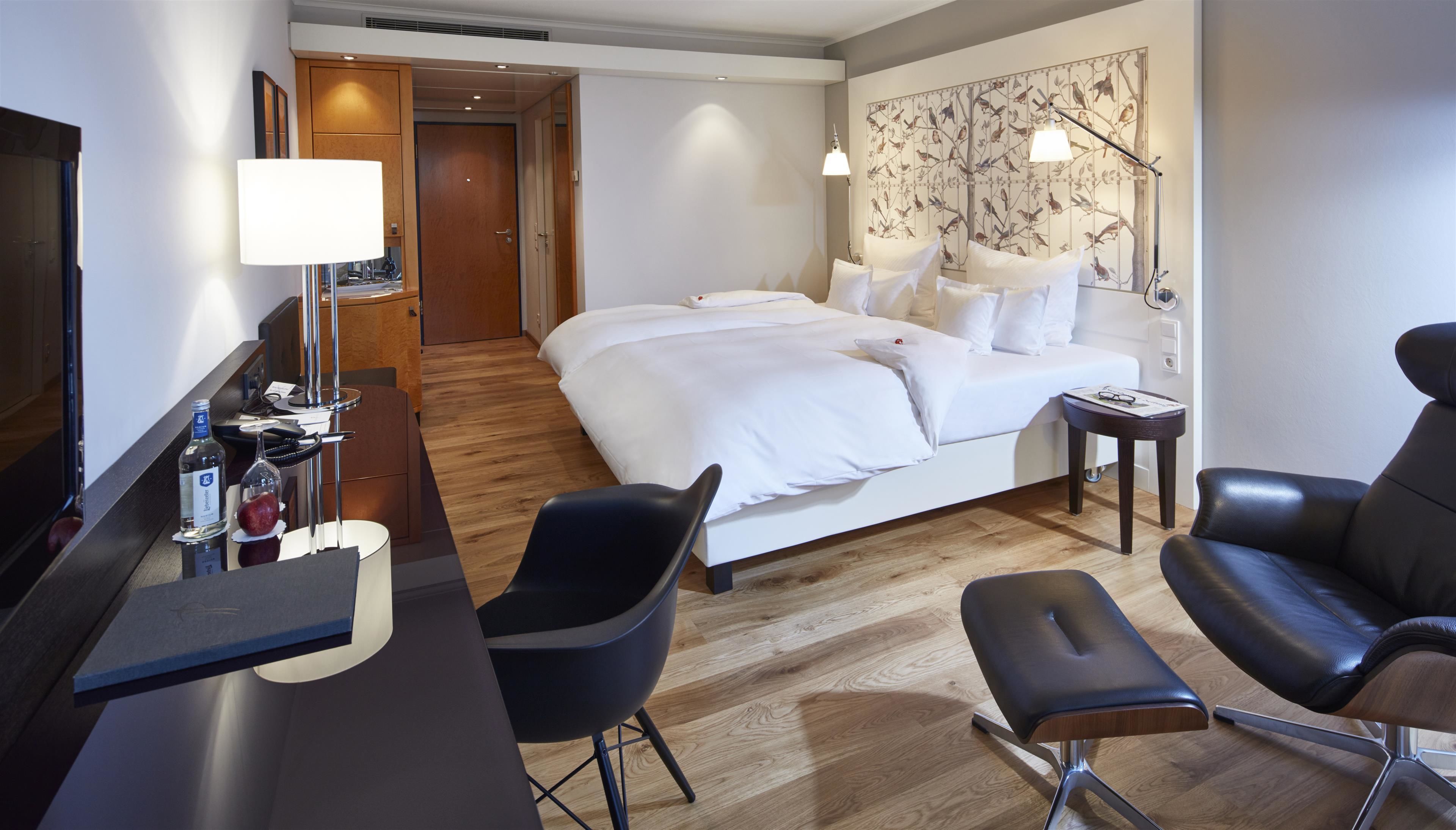 A hotel room with a bed, a desk, a chair, and a small table.