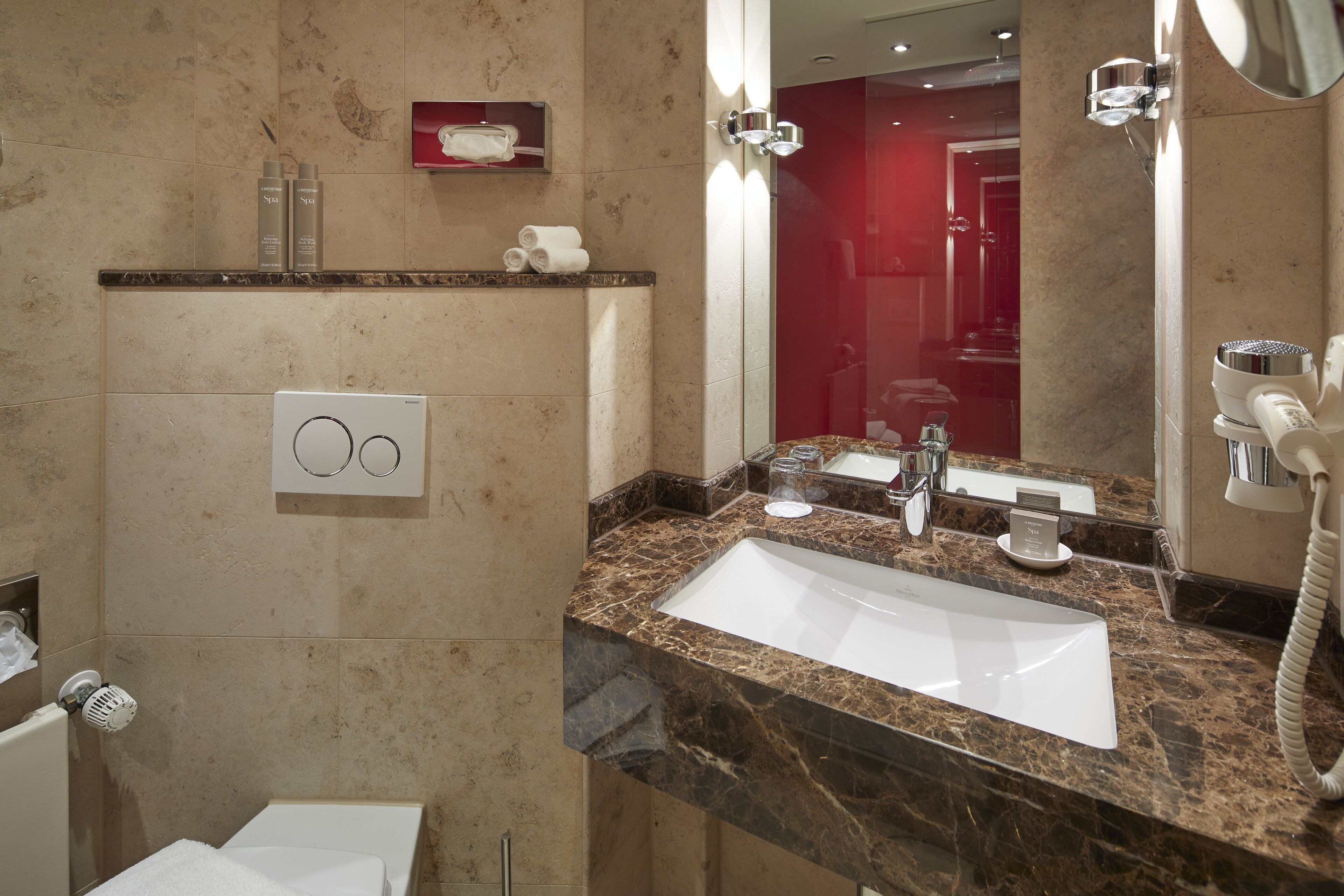 A bathroom with a marble sink, a mirror, and a towel rack.
