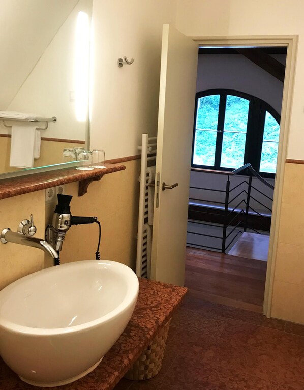 A bathroom with a white sink, a mirror, and a towel rack. There is a window with a view of a balcony. - Parkhotel Pforzheim (Pforzheim)