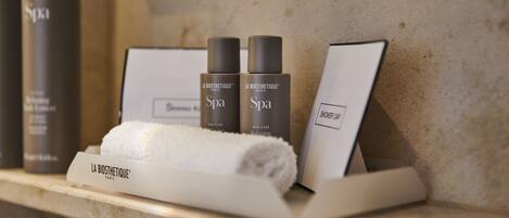 Un tocador de baño con un perchero, dos botellas de productos La Biosthétique Spa y una cortina de ducha.