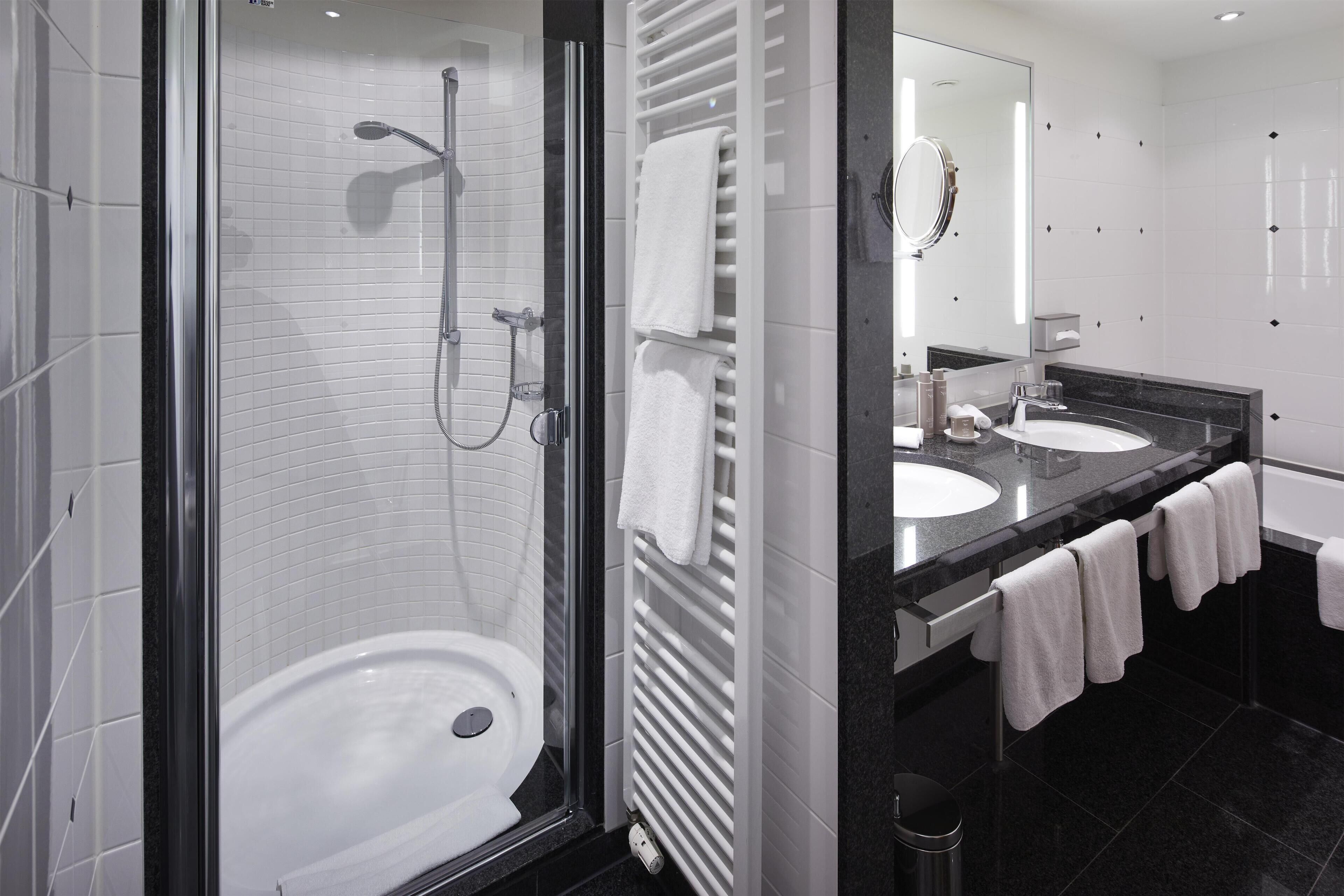 A modern bathroom with a glass-enclosed shower, a white sink, and a mirror above the sink.