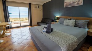 A hotel room with a large bed, a desk, and a view of the beach. - Hospitality Port Hedland (Port Hedland)