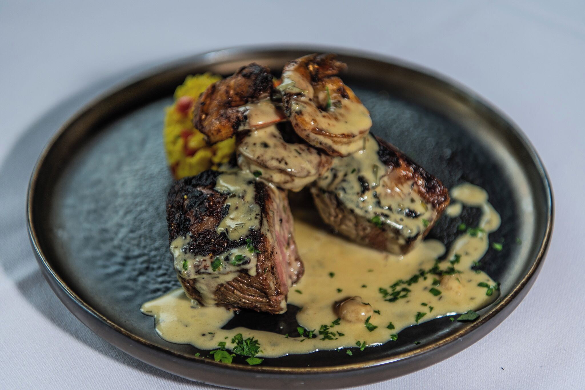 A plate of steak with mushrooms and a creamy sauce, garnished with herbs.