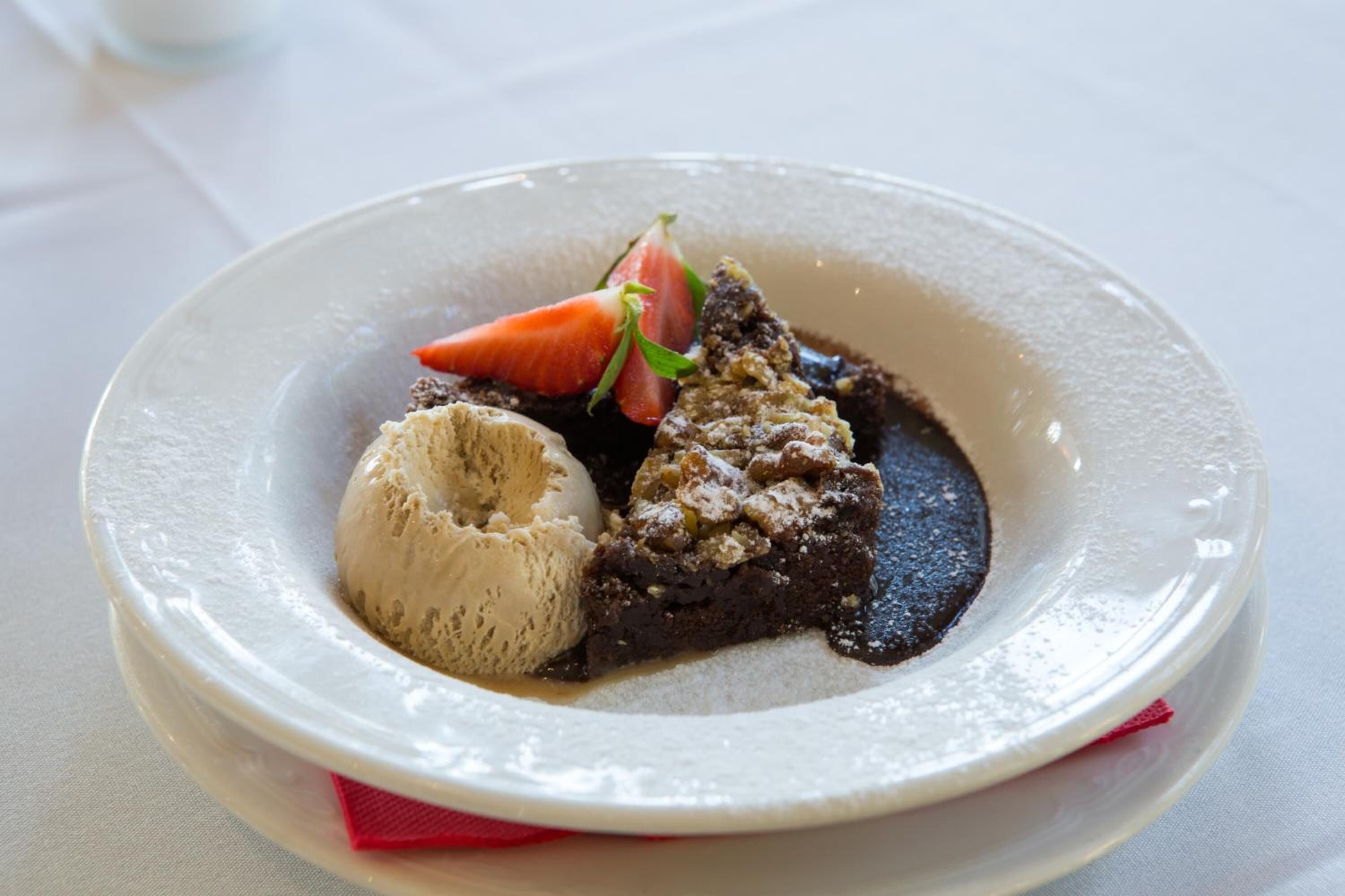 A dessert plate with a scoop of ice cream, a piece of cake, and a strawberry.