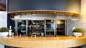 A bar area with a curved counter, shelves of bottles, and hanging glasses. - Hospitality Port Hedland (Port Hedland)
