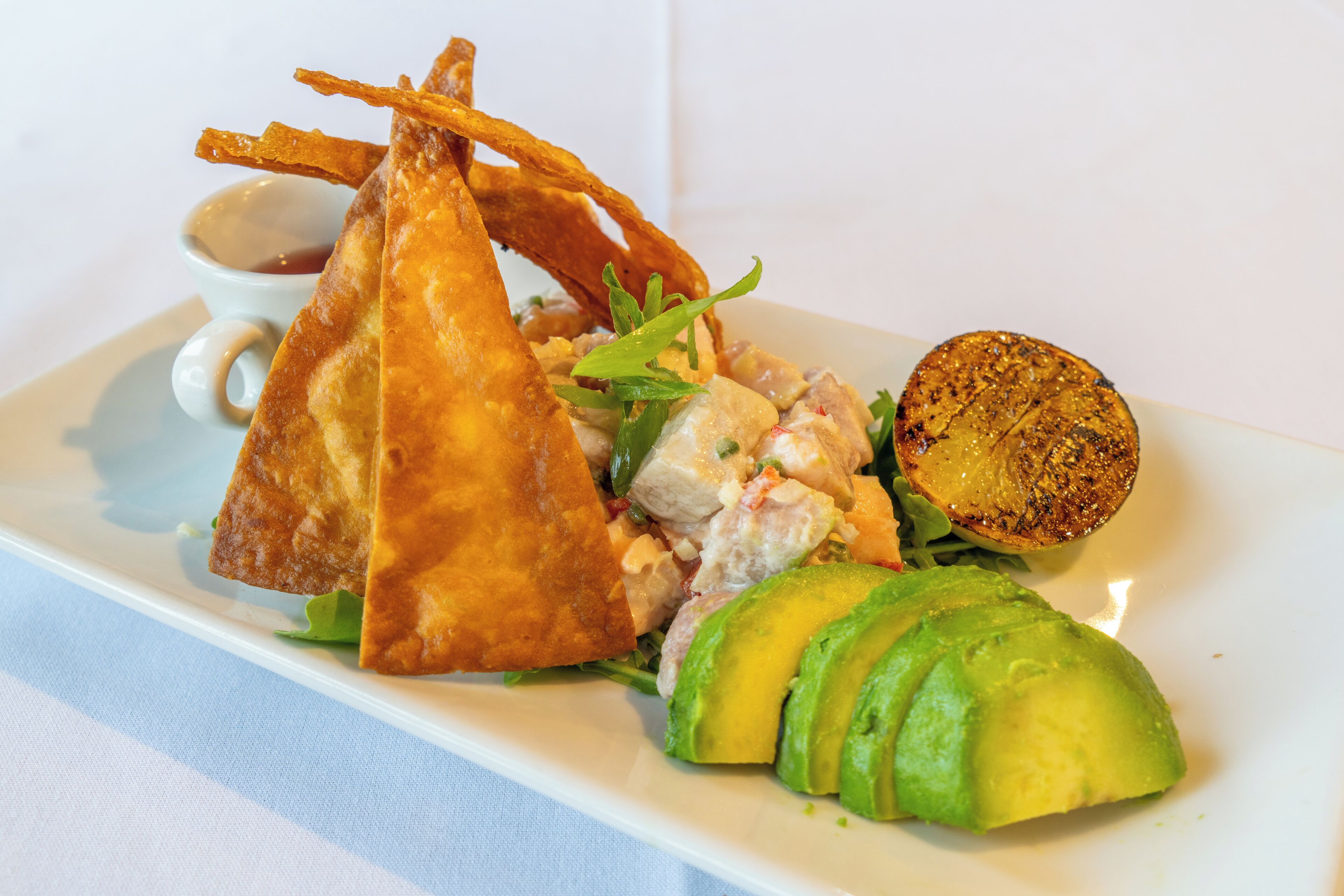 A plate with a salad, avocado slices, and fried items.