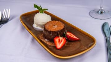 Un plat de postres amb un pastís de lava de xocolata, una bola de gelat de vainilla i maduixes.