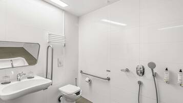 Un baño moderno con lavamanos, inodoro y ducha.