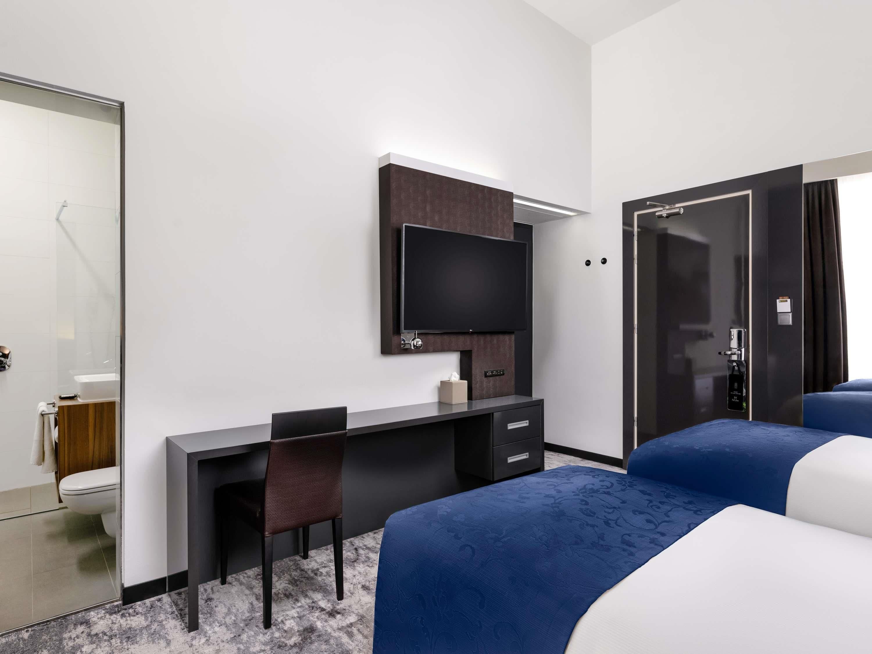 Une chambre d’hôtel équipée d’un lit, d’un bureau, d’une chaise, d’une télévision et d’une armoire.