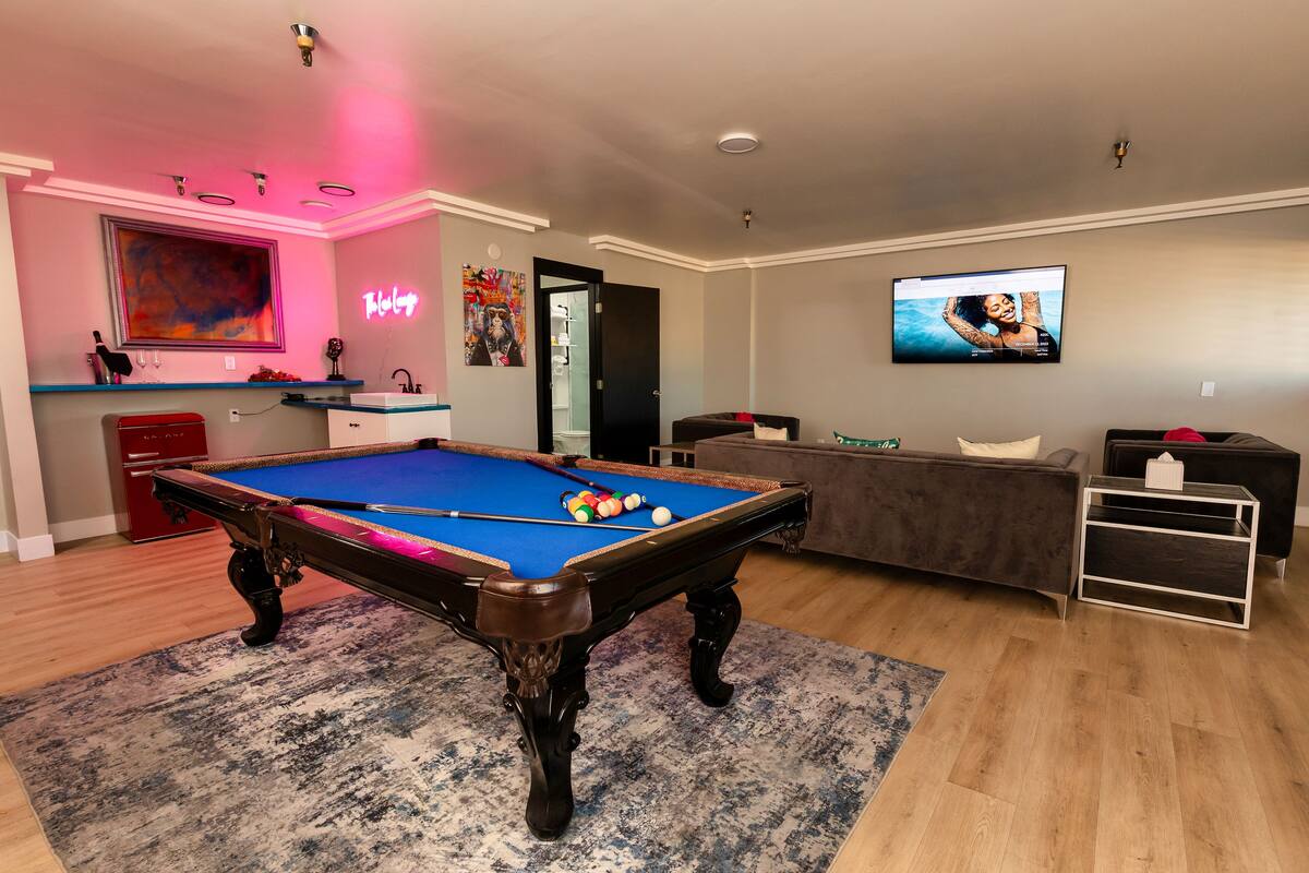 A modern living room with a pool table, a television, and a sofa.