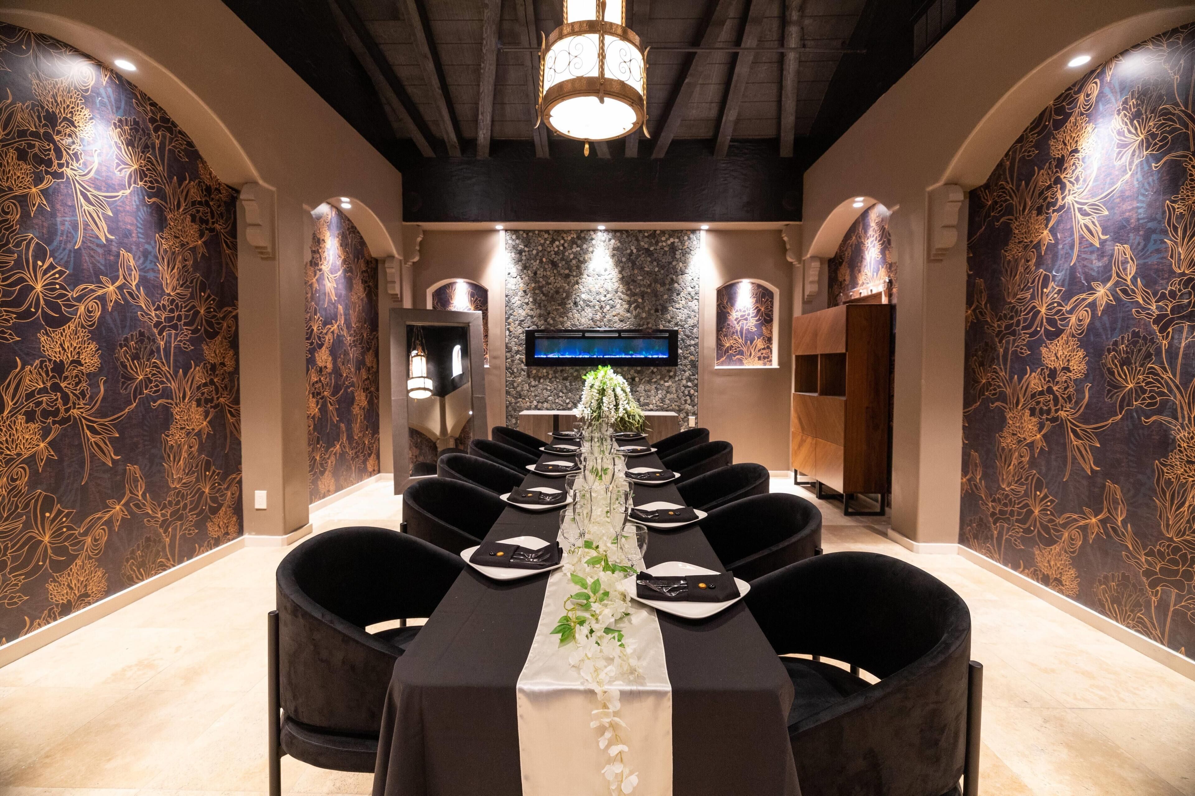 A conference room with a long table, black chairs, and a floral centerpiece.